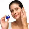 Nainen levittää silmänympärysvoidetta kasvoilleen, pitäen kädessään Repechage-merkin sinistä purkkia.